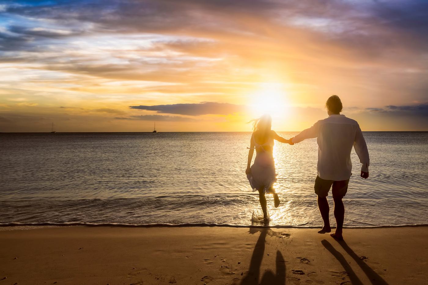 Couple running into the sea at sunset